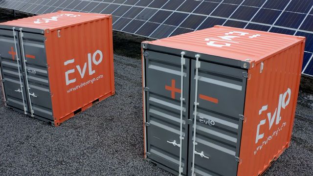 Two EVLO 500s, orange metal boxes with a silver front, in front of a solar panel array.